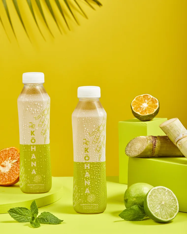 Botella de jugo de caña Kōhana Citrus, de color verde claro, el sabor más versátil de la línea