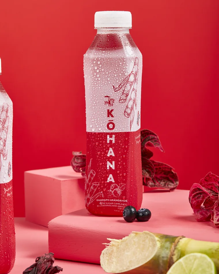 Botella de jugo de caña Kōhana Flor de Jamaica, de color rojo intenso, el sabor floral de la línea
